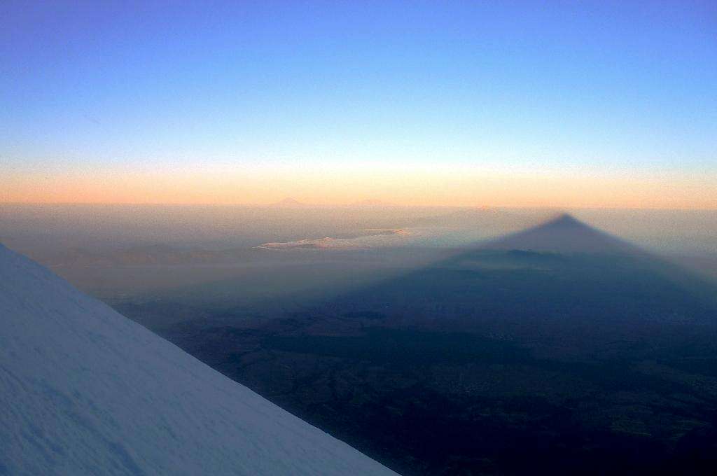 Shadow of Pico de Orizaba at sunrise, with a glance of Popocatépetl and Iztaccíhuatl at the horizon