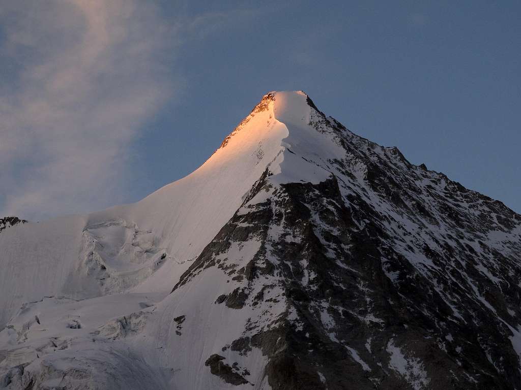 The very first rays of morning glow on the top of Obergabelhorn
