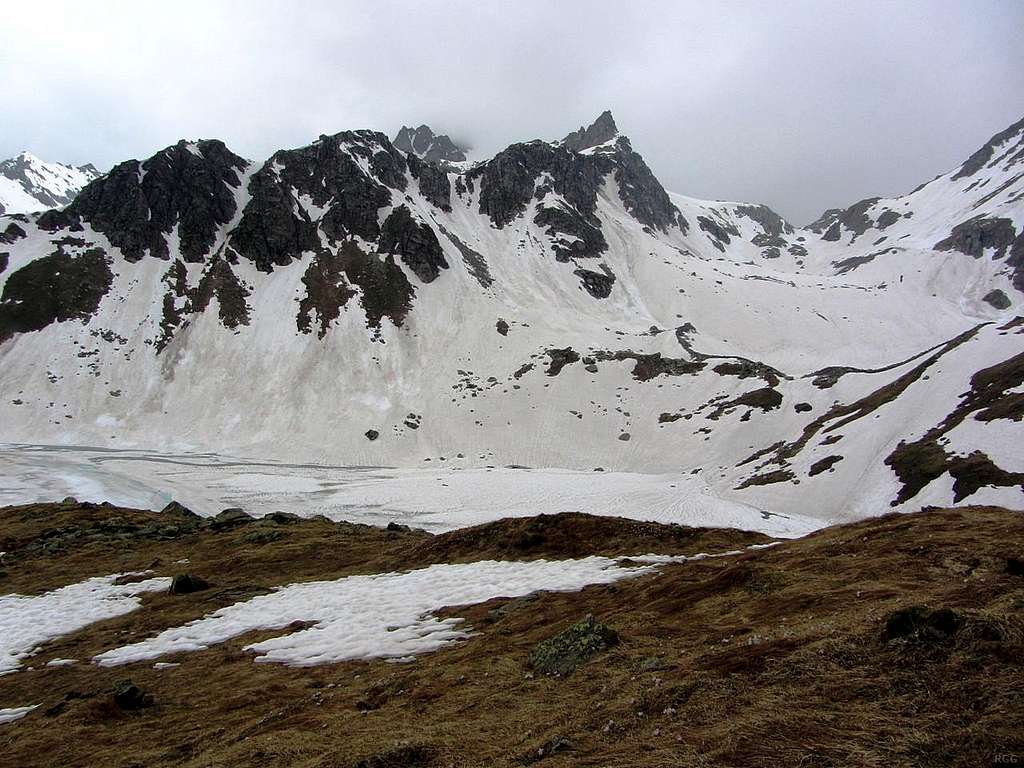 Lago Sruer in front of Torri di Vannino, with Punta d´Arbola behind, obscured by clouds. On the right is Passo del Vannino, at the head of Vallone del Vannino