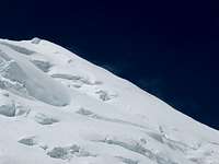 2 Sherpas dwarfed by the Kun summit ridge