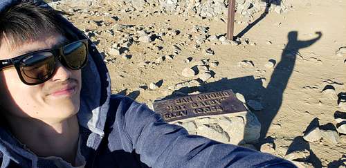 Summit selfie with sign in the background