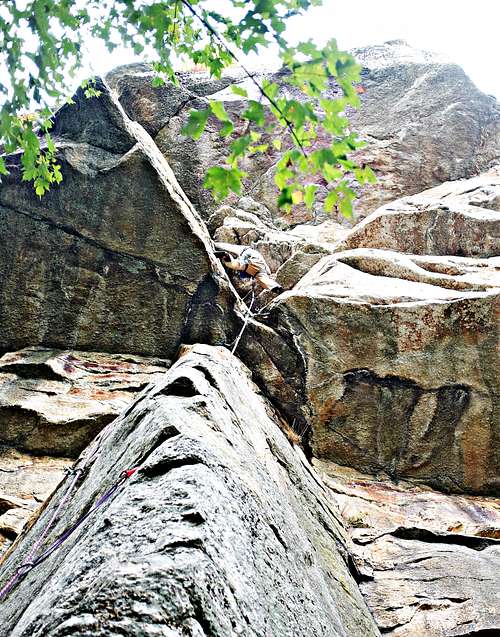 A climber stemming through the difficulties of 'Fat Stick'