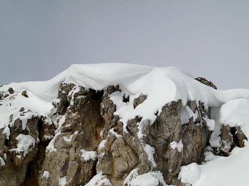 Small cornice of snow hanging over a small quarry